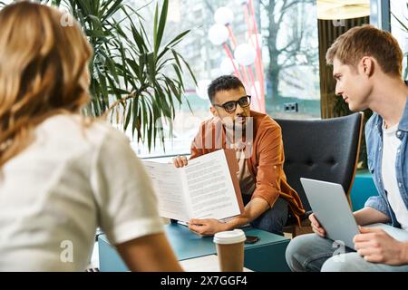 Gruppo di colleghi in uno spazio di coworking, brainstorming e revisione di documenti intorno a un tavolo in un ambiente aziendale moderno. Foto Stock