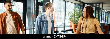 Colleghi multiculturali in abbigliamento casual che camminano insieme lungo un corridoio durante un viaggio d'affari. Foto Stock