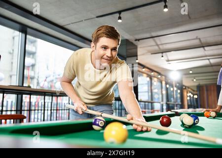 Due colleghi di un team di startup si divertono a giocare a biliardo in una camera spaziosa, immersi in un'amichevole competizione e relax. Foto Stock