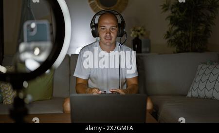 Giovane ispanico che registra video giocando a un videogame seduto sul divano a casa Foto Stock