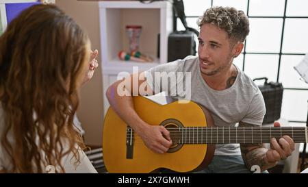 Un uomo e una donna si esercitano a cantare e suonare la chitarra in uno studio di musica casalinga. Foto Stock