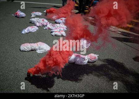 Pamplona, Spagna. 18 maggio 2024. Esibizione di bagliore rosso e lenzuola macchiate di sangue, simulando bambini uccisi durante la guerra nella Striscia di Gaza. Migliaia di persone hanno partecipato a una manifestazione per le strade di Pamplona chiedendo una Palestina libera. Credito: SOPA Images Limited/Alamy Live News Foto Stock