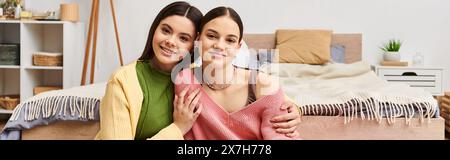 Due graziose ragazze adolescenti in un abbigliamento casual che chiacchierano e ridevano mentre si sedevano accanto a loro su un letto a casa. Foto Stock