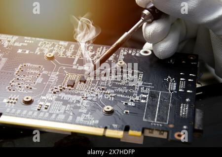 Tecnico che sta riparando circuiti, tecnico che ripara e salda circuiti riparazione scheda grafica Foto Stock