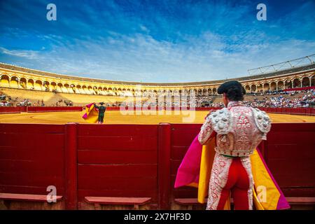 Un assistente osserva l'inizio di una corrida da a bordo campo a Real Maestranza, Siviglia. Foto Stock