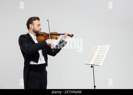 Violinista maschile barbuto che suona il violino davanti agli spartiti Foto Stock