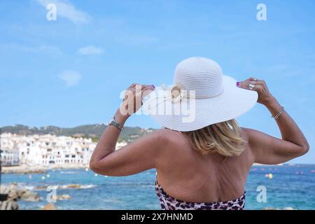 Vista posteriore di una donna matura turistica in bikini e con indosso un cappello in vacanza estiva Foto Stock