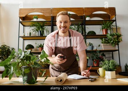 Un uomo in un grembiule tiene un cellulare in un'officina. Foto Stock