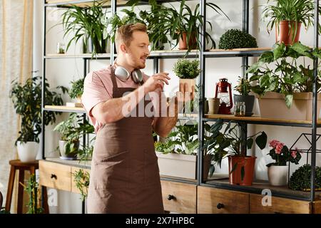 Un uomo si trova di fronte a uno scaffale pieno di varie piante in vaso in un piccolo negozio di piante, incarnando l'essenza della natura e dell'imprenditorialità. Foto Stock