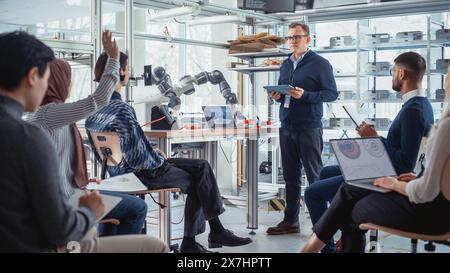 University Robotics Lecture: Insegnante che spiega l'ingegneria agli studenti utilizzando robot Arm. Gruppo diversificato di giovani ingegneri programmazione mano robotica. Concetto di istruzione superiore in informatica. Foto Stock