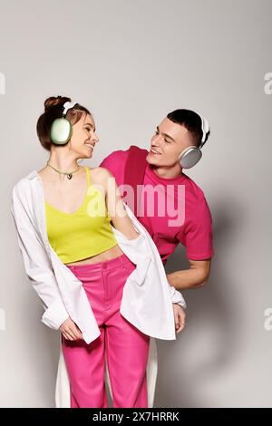 Un uomo e una donna, vestiti con stile, in piedi vicini in uno studio con sfondo grigio, che sembrano profondamente innamorati. Foto Stock