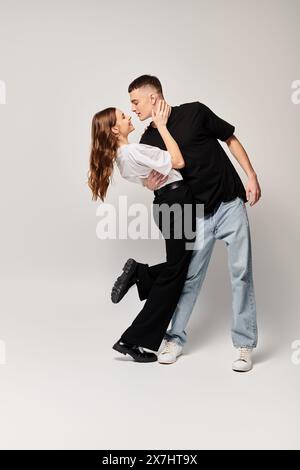 Una giovane coppia innamorata danza graziosamente insieme in uno studio, mostrando perfetta sincronizzazione e ammirazione reciproca. Foto Stock