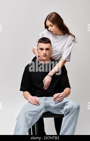 Una donna si siede graziosamente in cima a un mans Back, mostrando un momento amorevole e intimo tra la coppia. Foto Stock