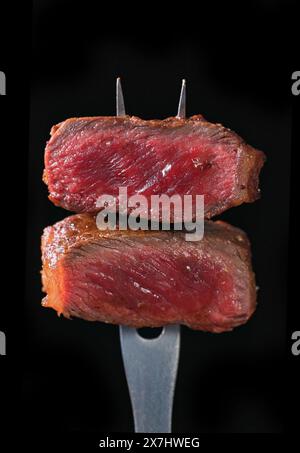 due pezzi di carne di manzo appena grigliata isolata su sfondo nero, messa a fuoco selettiva Foto Stock