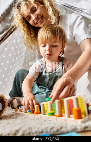 Una madre riccia e sua figlia si impegnano nel metodo Montessori, giocando con blocchi colorati a casa. Foto Stock