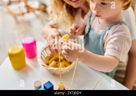 Una madre dai capelli ricci e sua figlia stanno scherzosamente esplorando diversi cibi insieme, adottando il metodo Montessori a casa. Foto Stock