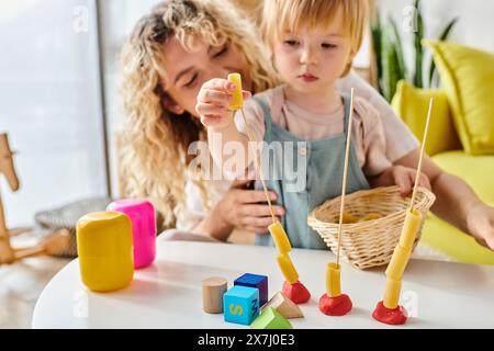 Una madre riccia e sua figlia si impegnano giocosamente con i giocattoli Montessori, promuovendo l'apprendimento pratico e la creatività. Foto Stock