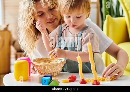Una madre dai capelli ricci e la figlia del bambino interagiscono giocosamente con i giocattoli educativi Montessori a casa. Foto Stock