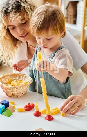 Una madre dai capelli ricci e sua figlia si impegnano nel metodo Montessori, costruendo e giocando gioiosamente Foto Stock