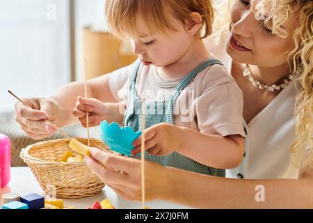 Una madre riccia e la figlia del bambino giocano felicemente con giocattoli educativi utilizzando il metodo Montessori a casa. Foto Stock