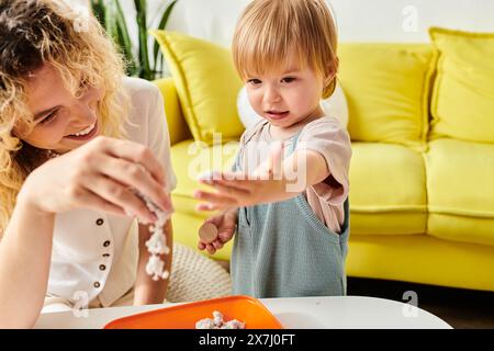 Una madre riccia e la figlia del bambino esplorano giocosamente e sperimentano vari prodotti alimentari utilizzando il metodo educativo Montessori a casa. Foto Stock