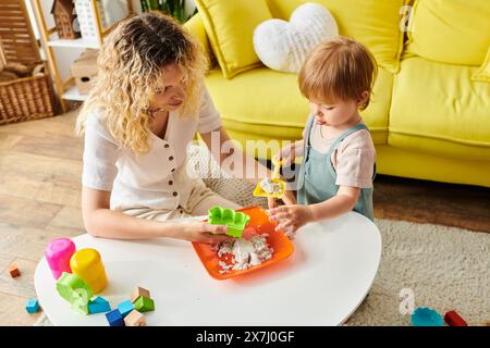 Una madre dai capelli ricci e sua figlia si impegnano nel metodo Montessori, giocando con i giocattoli a casa. Foto Stock