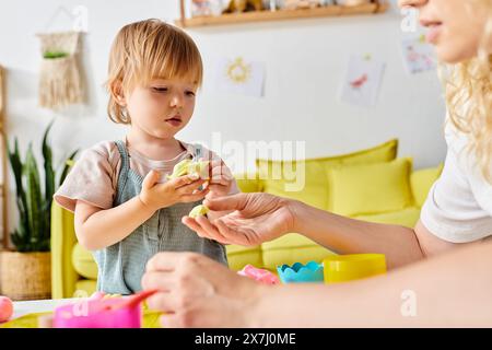 Una madre con i capelli ricci e la figlia del bambino intraprendono attività giocose con i giocattoli Montessori a casa. Foto Stock