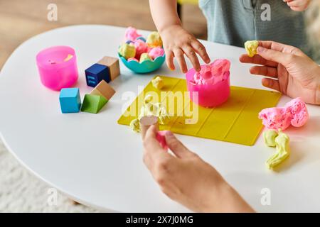 Un bambino è impegnato a modellare un impasto colorato su un tavolo, esplorando la creatività con il metodo Montessori. Foto Stock