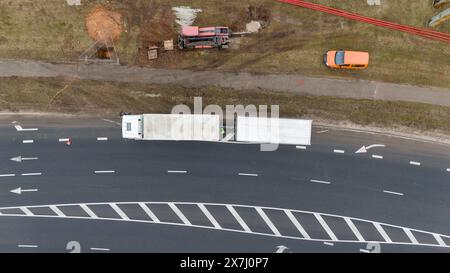 Fotografia con droni di operai edili, macchinari industriali che posano nuove condutture vicino a una strada durante il giorno nuvoloso primaverile Foto Stock