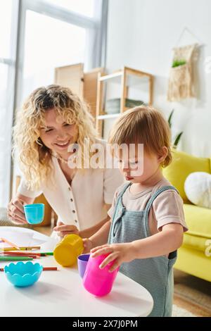 Una madre riccia e sua figlia si dedicano a divertenti attività di coppa Montessori a casa. Foto Stock