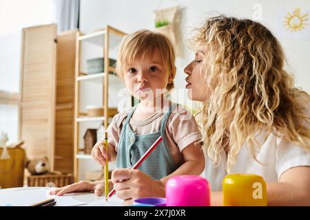 Una madre riccia e sua figlia si impegnano nel metodo di educazione Montessori a un tavolo. Foto Stock