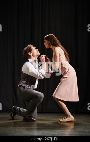 Un uomo si inginocchia accanto a una donna sul palco durante una prova teatrale. Foto Stock