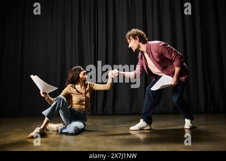 Un bell'uomo si inginocchia accanto a una donna sul pavimento in un ambiente teatrale. Foto Stock