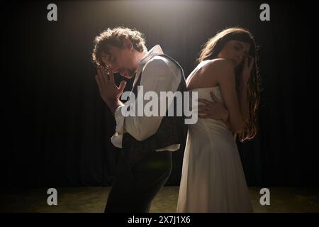 Un uomo e una donna stanno insieme in una stanza poco illuminata, provando per uno spettacolo teatrale. Foto Stock