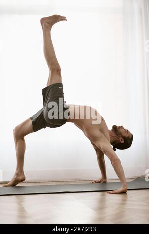 Un bell'uomo pratica una mano su un tappetino da yoga a casa sua. Foto Stock