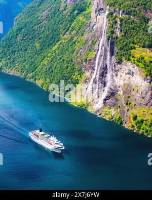 Una grande nave da crociera galleggia presso le famose cascate delle sette Sorelle nelle acque cristalline del fiordo Sunnylvsfjorden vicino al villaggio di Geiranger nella Norvegia occidentale Foto Stock