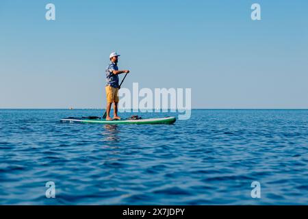 29 luglio 2022. Dalaman, Turchia. Uomo che nuota sulla tavola SUP a pale sul mare blu. Stile di vita estivo attivo Foto Stock