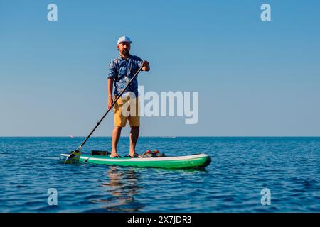 Luglio 29, 2022. Dalaman, Turchia. Uomo in camicia hawaiana a bordo di paddle SUP sul mare blu. Stile di vita estivo attivo Foto Stock