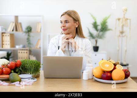 Nutrizionista che lavora sul laptop e scrive un programma dietetico per il paziente. Foto Stock