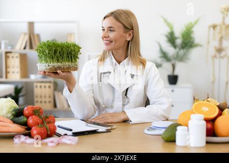 Affascinante donna caucasica in cappotto medico con microgreen. Foto Stock