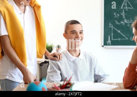 Adolescente in sedia a rotelle con i suoi compagni di classe a scuola Foto Stock