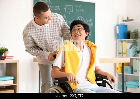 Adolescente con il suo compagno di classe in sedia a rotelle a scuola Foto Stock