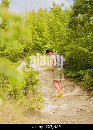 Donna di mezza età con zaino che cammina lungo il sentiero della foresta Foto Stock