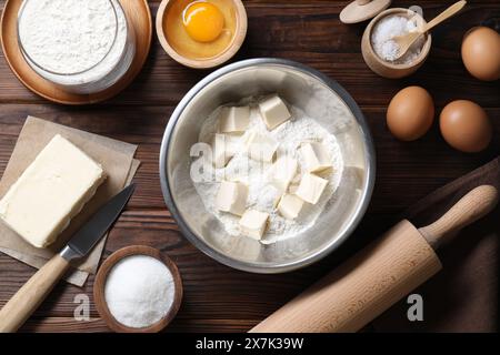 Preparazione di pasta frolla. Mattarello, coltello e diversi ingredienti per impastare su un tavolo di legno, in piano Foto Stock