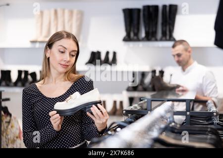 L'acquirente femminile guarda le calzature della nuova collezione e acquista un nuovo paio di mocassini Foto Stock