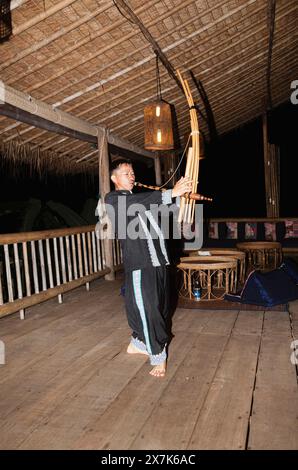 Un uomo hmong suona uno strumento musicale a Chiang Khong, nella provincia di Chiang Rai, nel nord della Thailandia, in colorato costume locale tradizionale Foto Stock