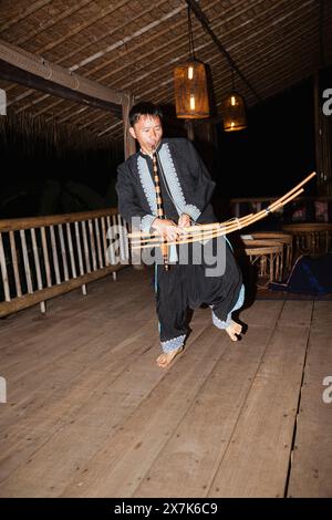 Un uomo hmong suona uno strumento musicale a Chiang Khong, nella provincia di Chiang Rai, nel nord della Thailandia, in colorato costume locale tradizionale Foto Stock