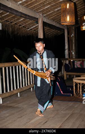 Un uomo hmong suona uno strumento musicale a Chiang Khong, nella provincia di Chiang Rai, nel nord della Thailandia, in colorato costume locale tradizionale Foto Stock