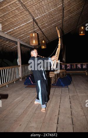 Un uomo hmong suona uno strumento musicale a Chiang Khong, nella provincia di Chiang Rai, nel nord della Thailandia, in colorato costume locale tradizionale Foto Stock