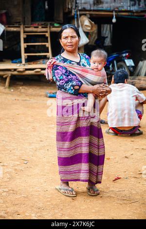 La madre Lahu porta un bambino in una fionda nel villaggio di Ban Kiew Karn a Lanjia Lodge, Chiang Khong nella provincia di Chiang Rai, nel nord della Thailandia Foto Stock